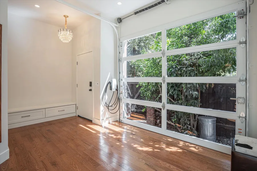 A finished room with a glass garage door, oak floor, and a built-in bench.