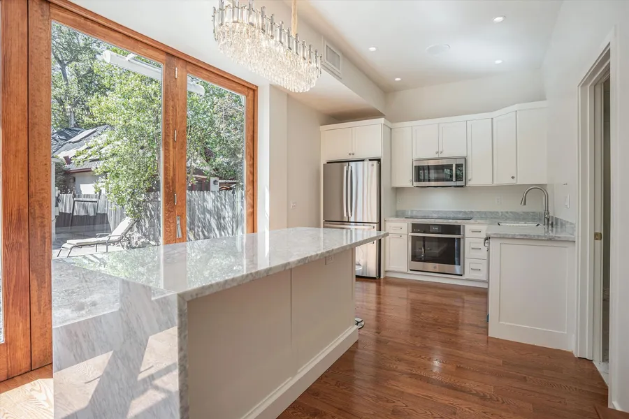 A kitchen island with a marble waterfall edge and wood-framed glass doors.