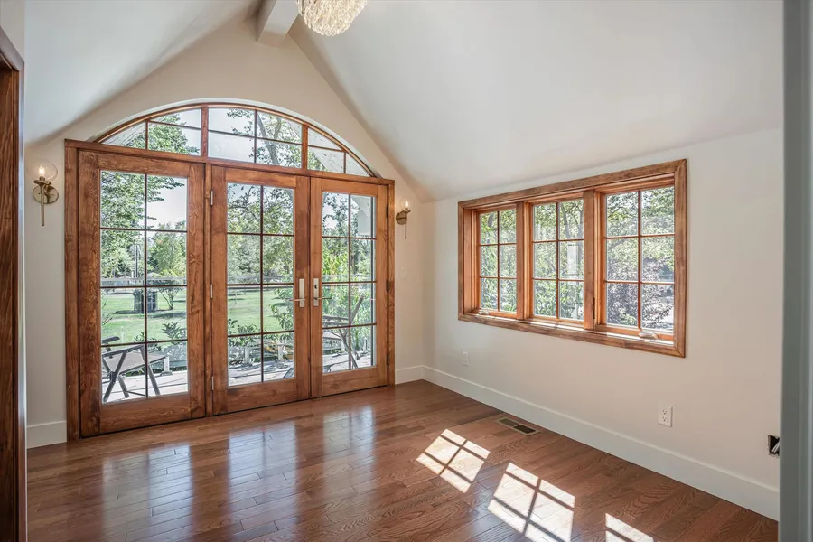 An upstairs room with arched wood French doors and a run of wood-framed windows.