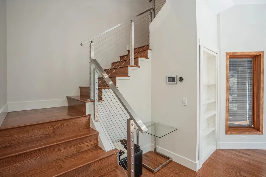 An oak stair with white risers and a stainless cable railing.