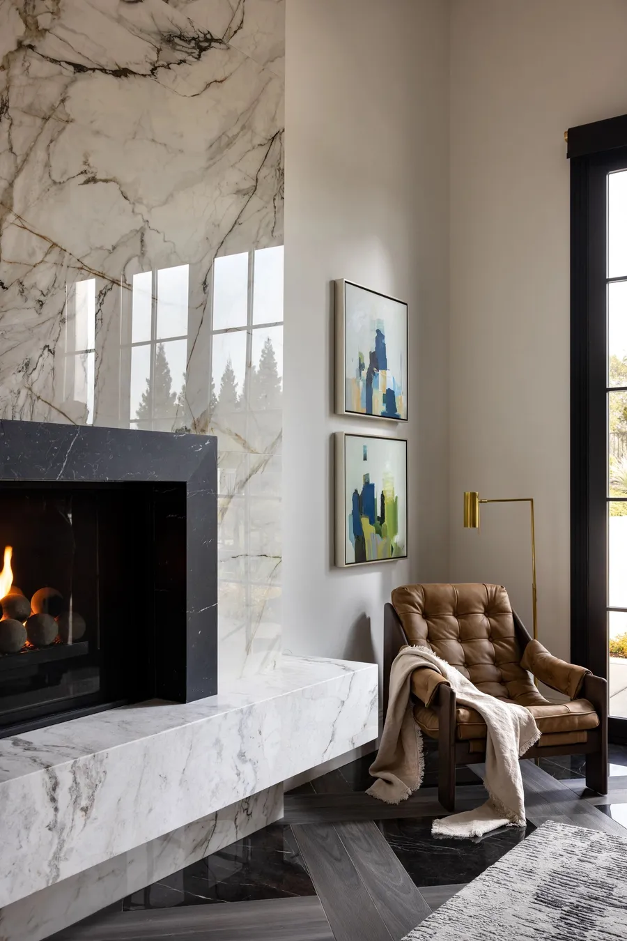 A floor-to-ceiling marble fireplace beside a leather armchair.