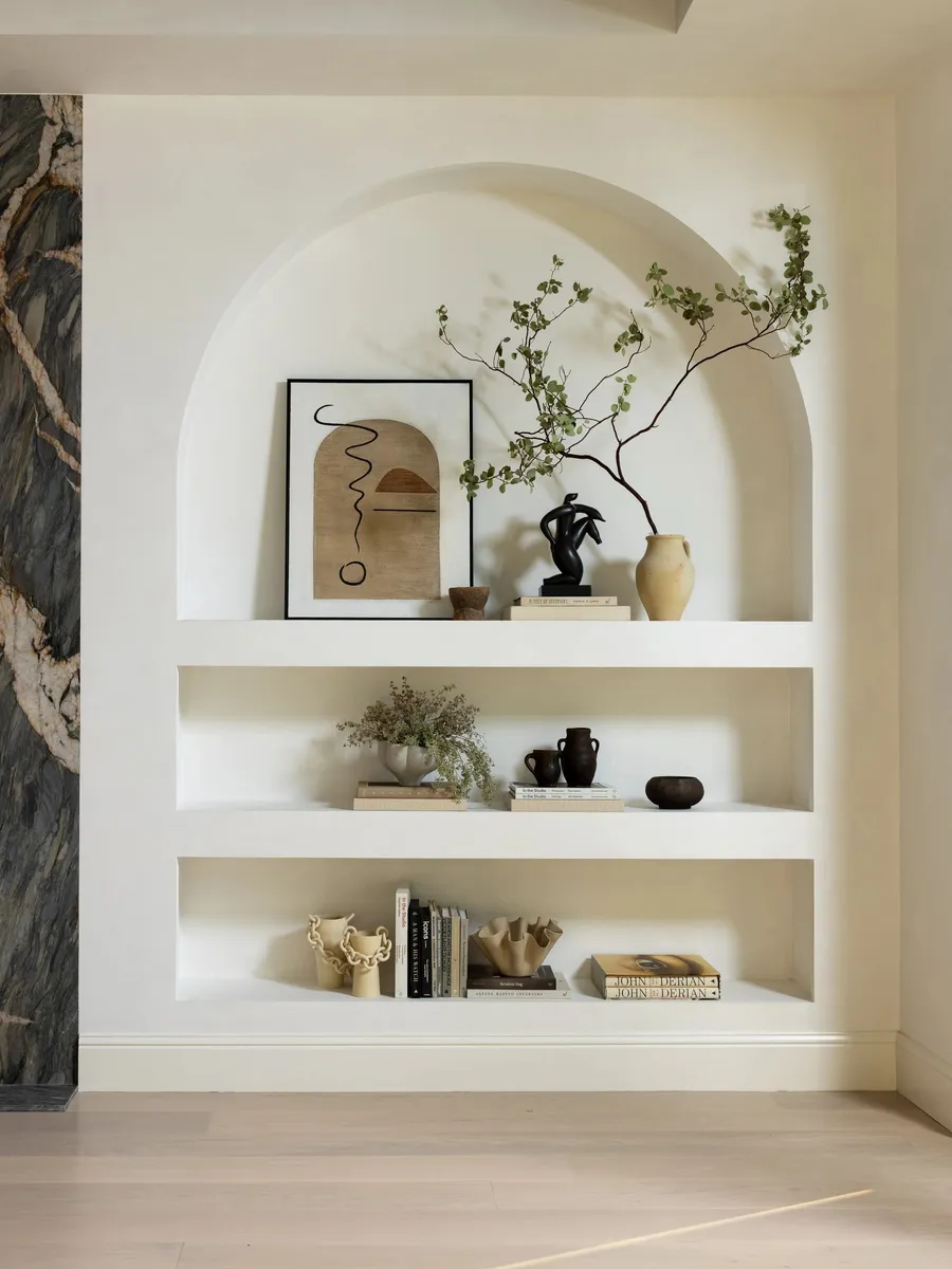 An arched plaster wall niche with recessed shelves.