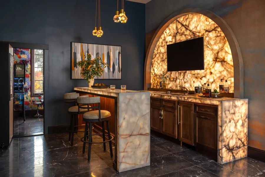 A home bar with a backlit stone arch, dark millwork, and marble floors.