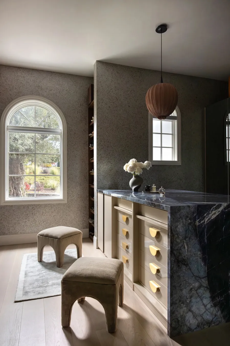 A dressing room with a blue marble island and custom drawers.