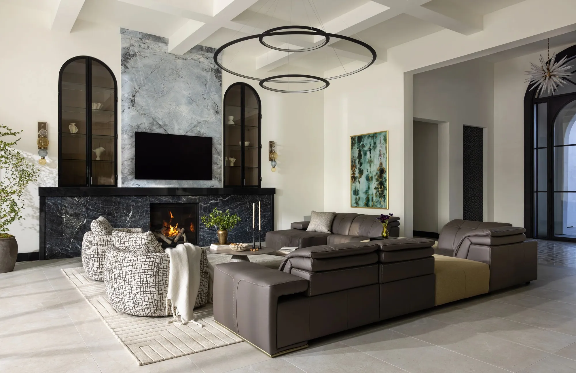 A living room with a marble fireplace, arched cabinets, and a coffered ceiling.